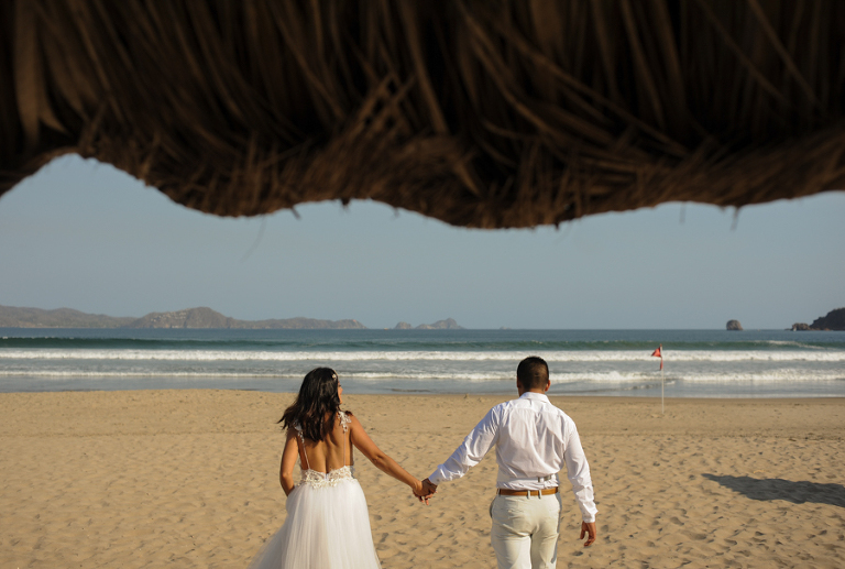 Los novios caminando hacia el mar